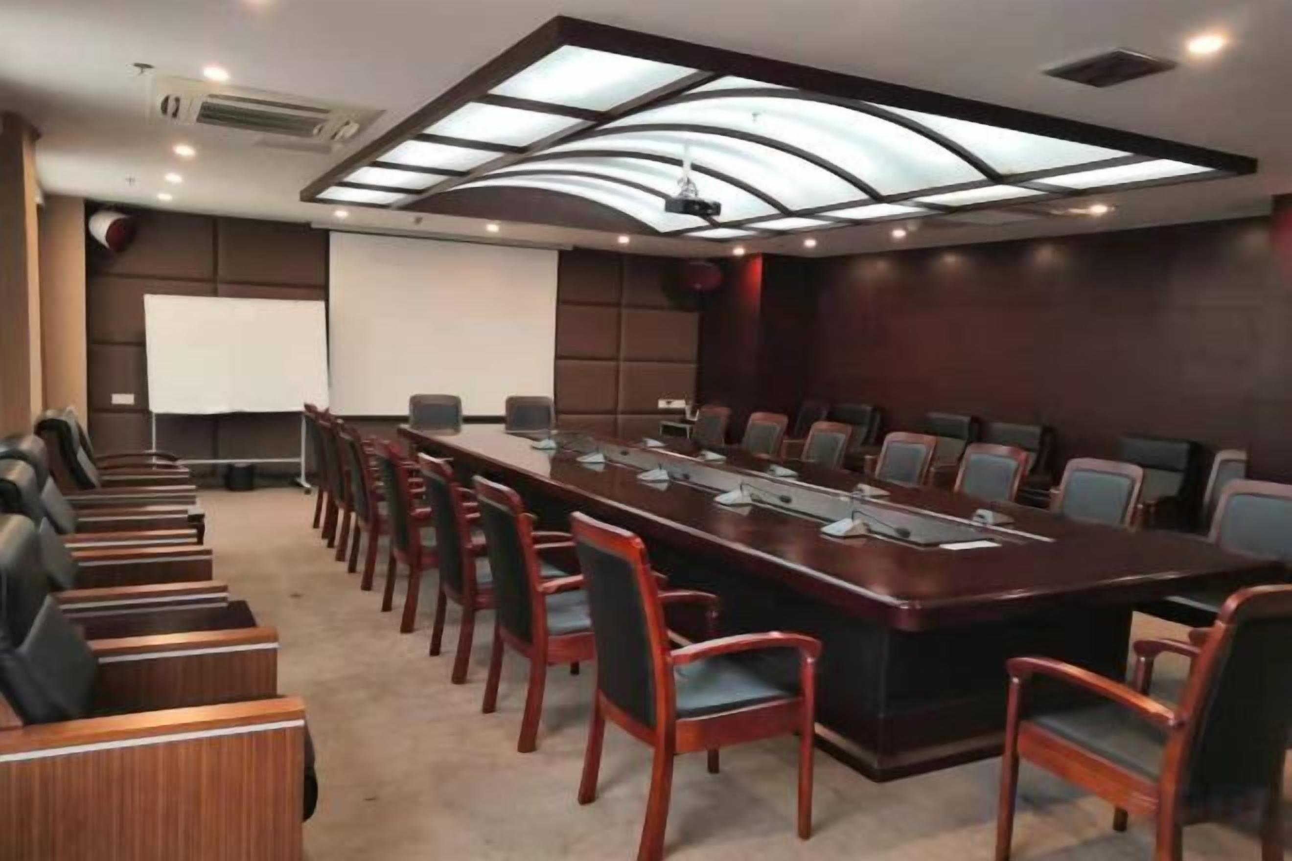 A conference room with a long table, chairs, a projector screen, and a whiteboard.