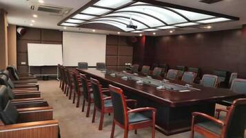 A conference room with a long table, chairs, a projector screen, and a whiteboard.