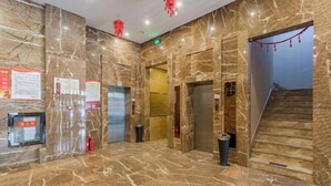 A marble-floored lobby with elevators, a staircase, and red hanging decorations. - Wancheng Hotel (Qianshan)