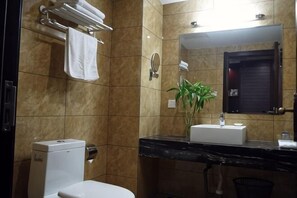 A bathroom with a toilet, sink, mirror, towel rack, and a potted plant. - Wancheng Hotel (Qianshan)