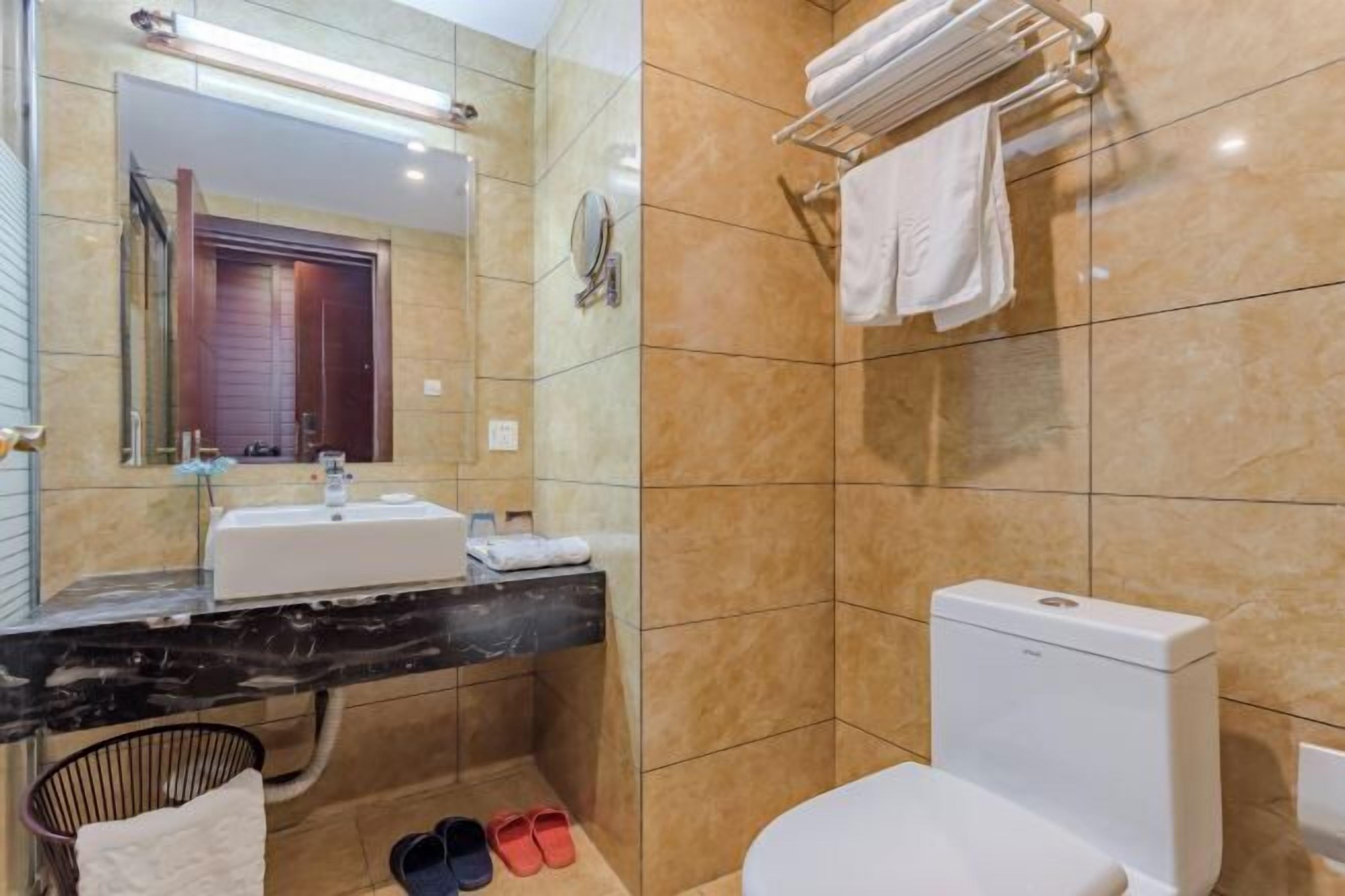 Un baño moderno con lavamanos de mármol, inodoro y toallero.