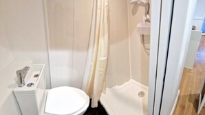 A small, modern bathroom with a toilet, shower, and sink. - Cute Studio Apartment in South Croydon (South Croydon)