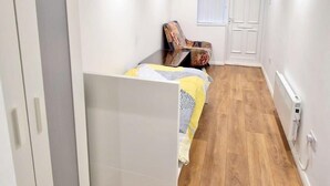 A compact bedroom with a bed, a wardrobe, a chair, and a small table. - Cute Studio Apartment in South Croydon (South Croydon)
