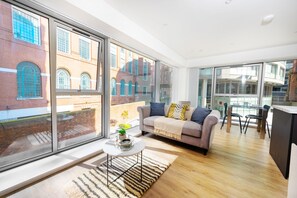 A modern living room with a sofa, coffee table, and large windows overlooking a brick building.