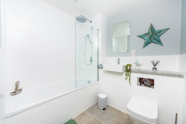 A modern bathroom with a glass-enclosed shower, a white toilet, a sink with a vanity, and a star decoration on the wall.