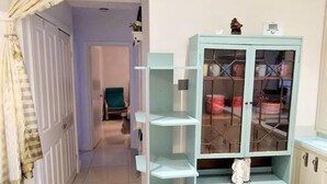 Una stanza con un armadietto azzurro con ante in vetro, una porta bianca e una tenda.