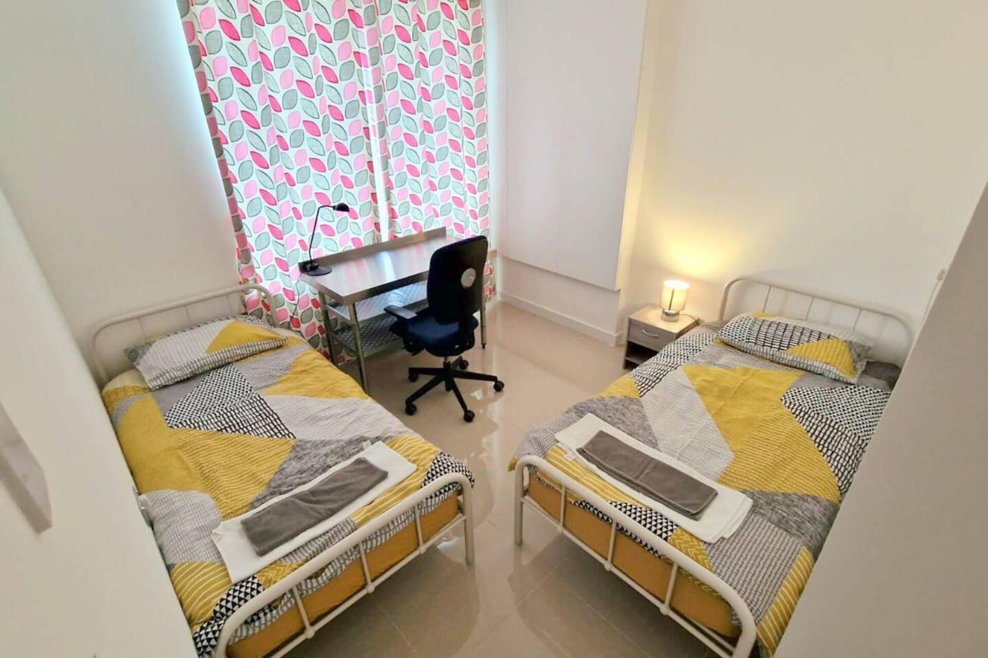 A room with two beds, a desk, and a chair.