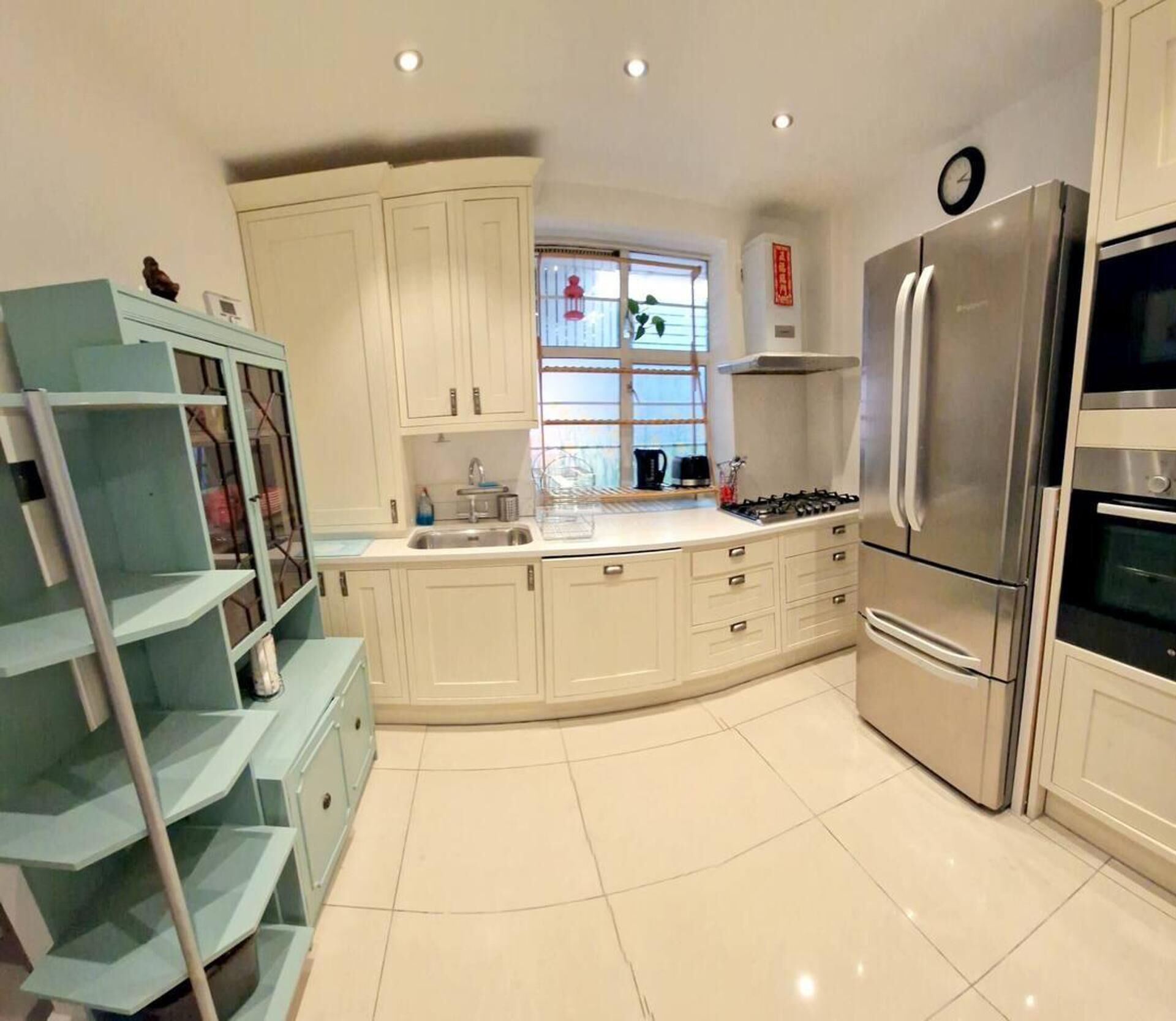 Una cucina moderna con mobili bianchi, un frigorifero in acciaio inossidabile e una finestra vista esterna.