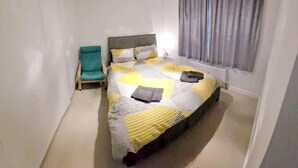 Una camera da letto con un letto, una sedia e una finestra con tende.