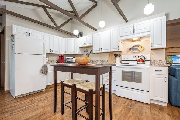A kitchen with white cabinets, a wooden table, and a red kettle. - Cub House by Taylor Made Deep Creek (McHenry)