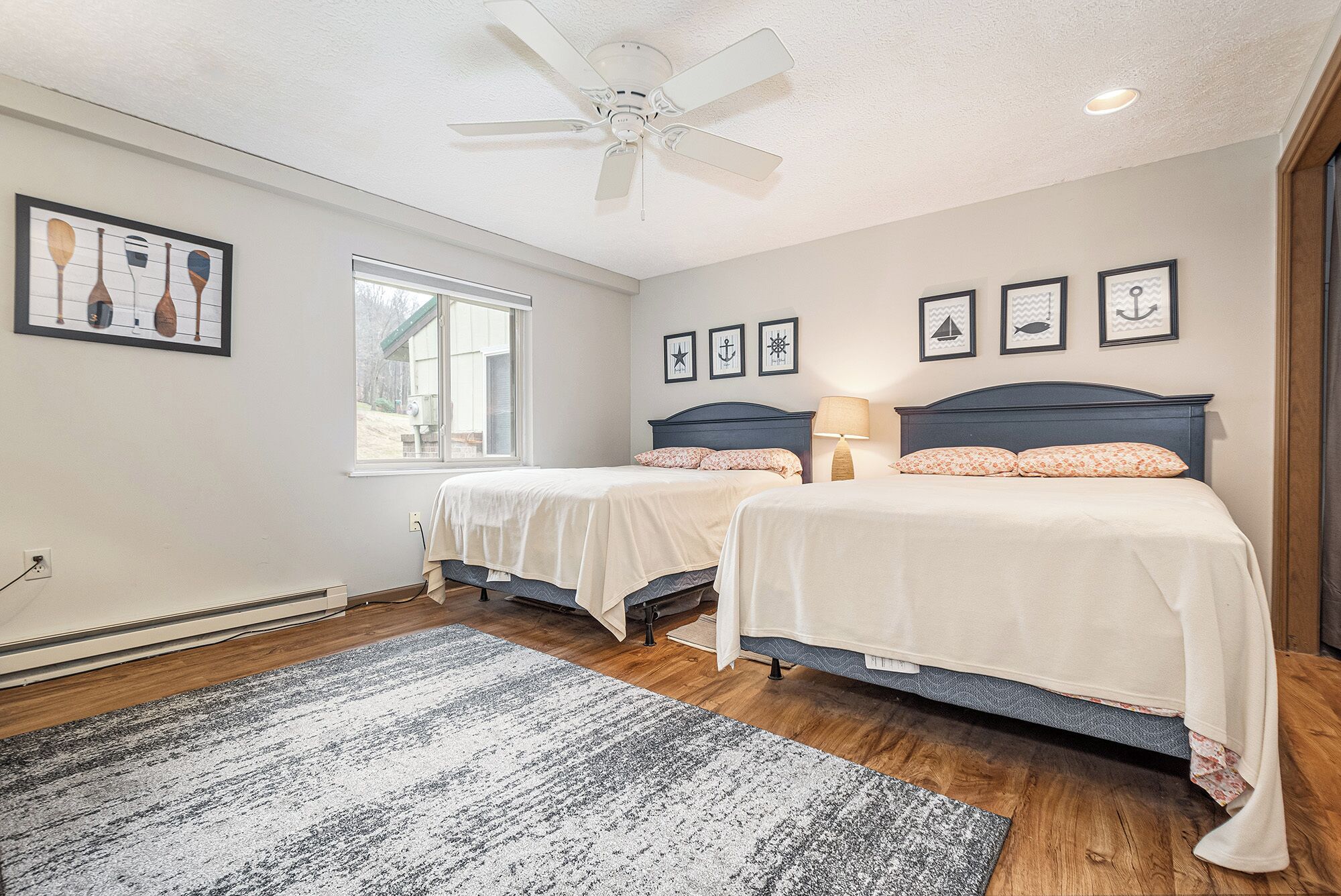 A bedroom with two beds, a ceiling fan, and a window.
