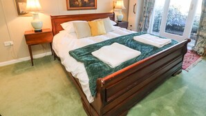 Un lit bien fait, agrémenté d’un plaid vert, deux tables de chevet avec des lampes et des œuvres d’art encadrées accrochées aux murs.