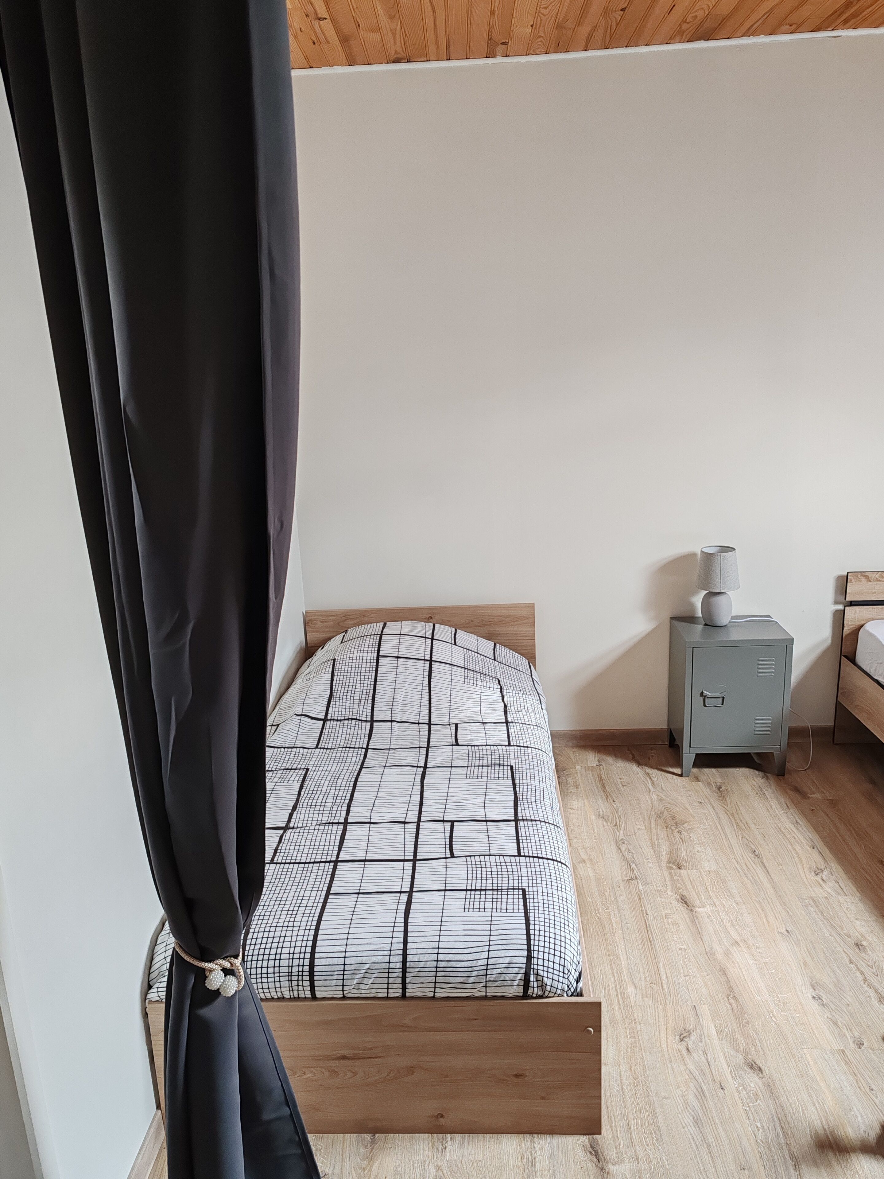A bedroom with a wooden bed, a nightstand, and a grey cabinet.