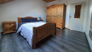 Ein Schlafzimmer mit einem hölzernen Bett, einem Nachttisch, einem Kleiderschrank und einer Tür mit Fenster.