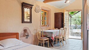 A bedroom with a bed, a table with chairs, a window, and a view of the outside. - Sage House (Trpanj)