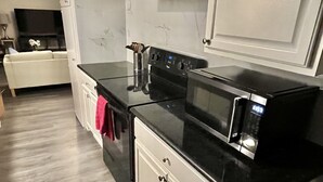 A modern kitchen with white cabinets, a black countertop, and a stainless steel range hood. - 5522 David & Jennie’s place 5 minutes to a community park (Houston)