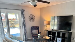 A modern living room with a sectional sofa, a glass coffee table, a dark armchair, a TV, and a ceiling fan. - 5522 David & Jennie’s place 5 minutes to a community park (Houston)