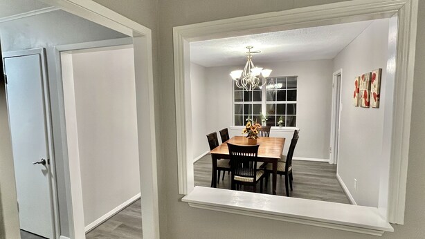 A dining area with a wooden table and chairs, a chandelier, and a window with a view. - 5522 David & Jennie’s place 5 minutes to a community park (Houston)