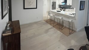 A modern kitchen with white cabinets, stainless steel appliances, and a central island with bar stools. - Updated Modern House North Dallas! (Dallas)