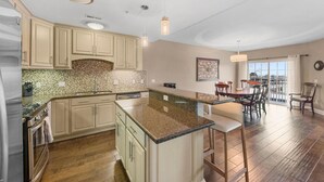 Une cuisine spacieuse dotée de plans de travail en granit, de meubles en bois et d’un coin repas offrant une vue agréable.