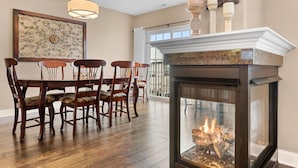 Un coin repas agrémenté d’une cheminée, de chaises en bois, d’une table et d’un élément décoratif mural.