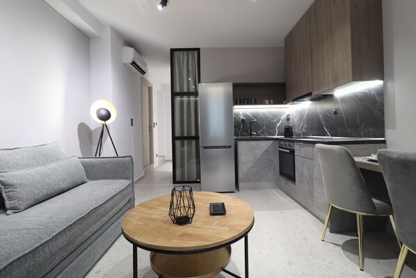 A modern living room with a grey sofa, a round wooden coffee table, and a dining area with grey chairs.