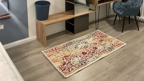 Ett modernt, kompakt rum med ett inbyggt skrivbord, en stol, en stor matta och ett element.