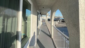 A covered outdoor corridor with windows and a railing, leading to a view of the cityscape. - Arlo Motel (Inglewood)