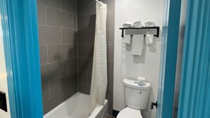 A bathroom with a shower, toilet, and a towel rack. - Arlo Motel (Inglewood)