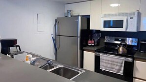 Une cuisine compacte équipée d’un réfrigérateur, d’un four à micro-ondes, d’une cuisinière et d’un évier.
