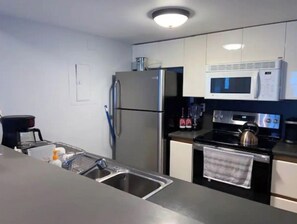 Enjoy cooking in this fully equipped kitchen with a refrigerator, microwave, stove, sink, and kettle.