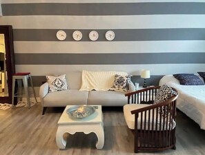 Relax in this stylish living room with a striped wall, sofa, and wooden rocking chair.