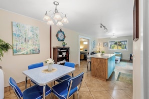 A dining area with a table and chairs, a kitchen with a blue island, and a living area with a sofa and a window. - Fern Creek - Murphys Vacation Rentals (Murphys)