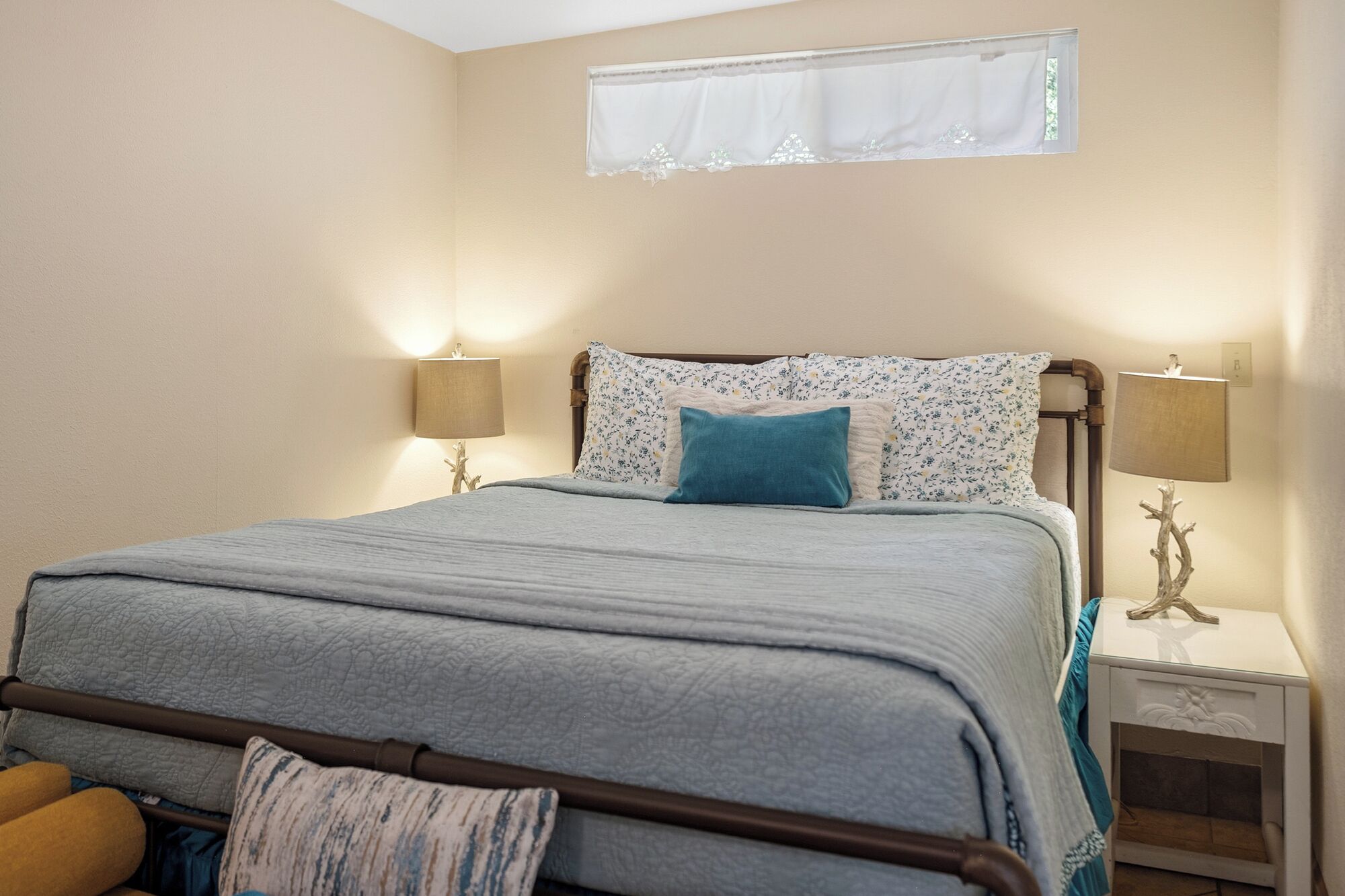 A bedroom with a bed, two bedside lamps, a window, and a nightstand.
