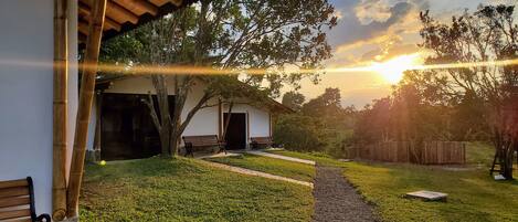 Una casa con porche cubierto, jardín césped y valla de madera.