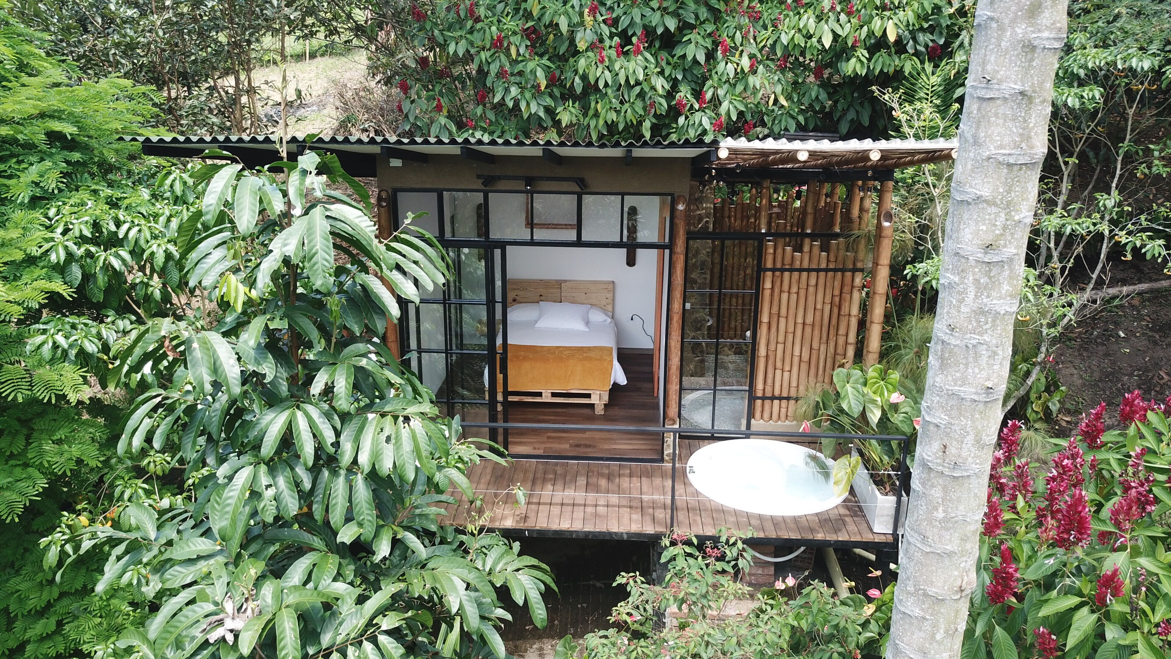 A small, rustic cabin with a wooden bed, a glass door, and a wooden deck.