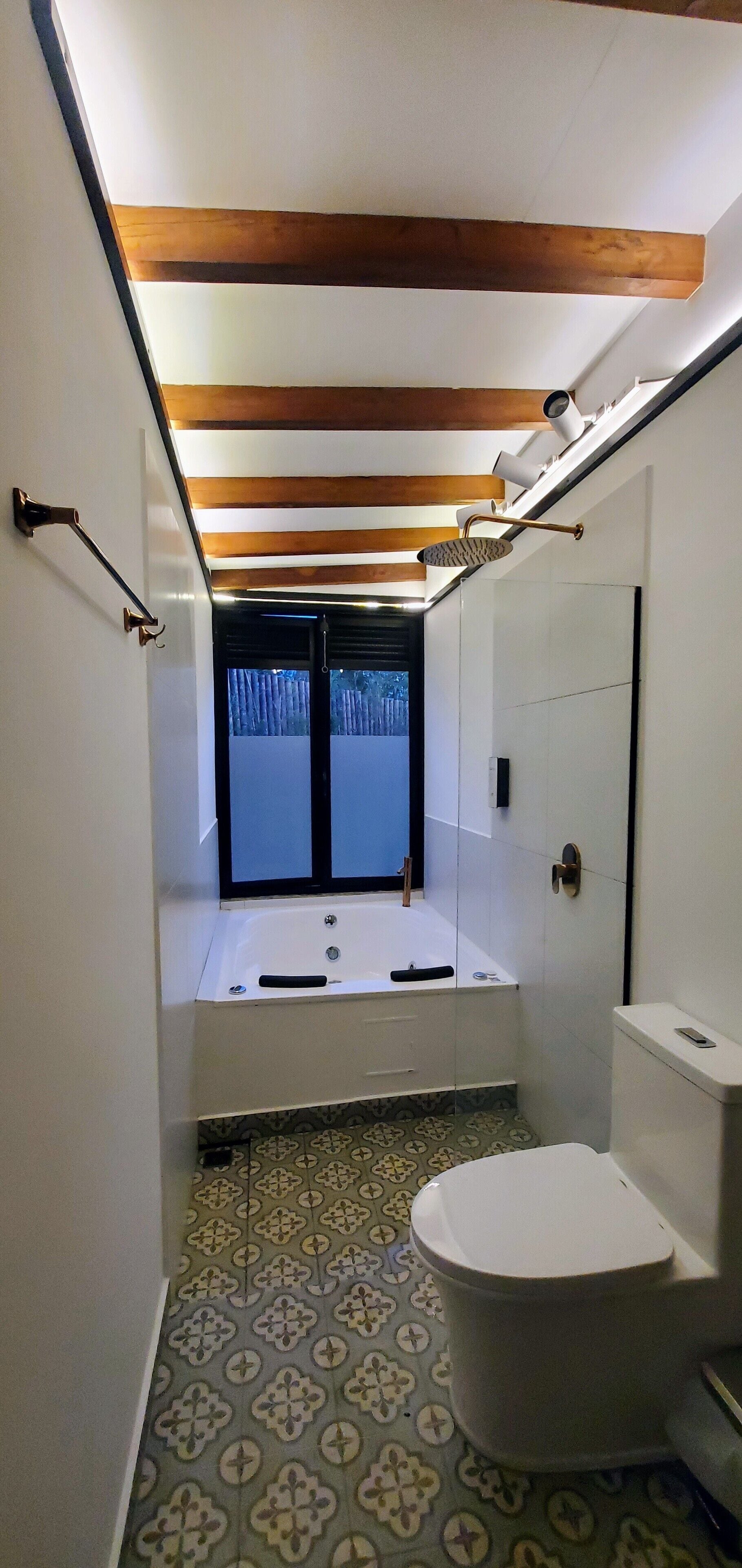 Un baño con bañera, inodoro y suelo de baldosas estampadas.
