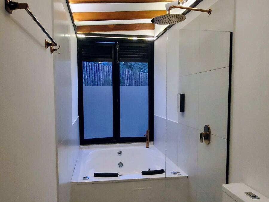 A bathroom with a bathtub, toilet, and patterned floor tiles.