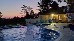 Una piscina con solarium, sdraio e un edificio sullo sfondo.