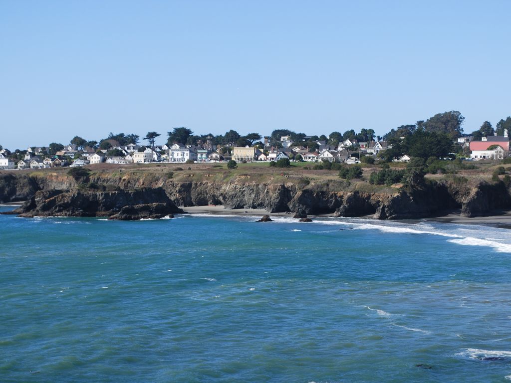 A coastal town with houses along the shore and rocky cliffs.