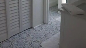 Un corridoio con pavimento decorato, una porta bianca e una parete bianca con un quadro incorniciato.