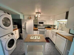 A compact kitchen with a washing machine, a microwave, a stove, and a sink. - Spacious 2-Bedroom Townhome Steps Away From Beach (St. Augustine)