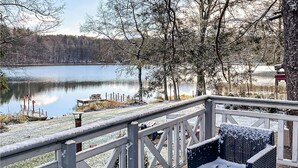Una terraza de madera con vistas a un lago y árboles.