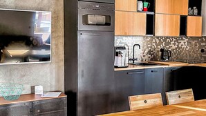 Una cocina moderna con horno integrado, cafetera y armarios de madera.