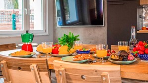 Una escena de desayuno con una mesa preparada para dos personas, platos de comida, vasos de jugo de naranja y una botella de jugo.