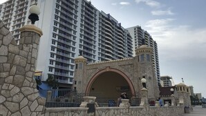 Un hotel moderno de gran altura con varios balcones y una entrada con arco de piedra.