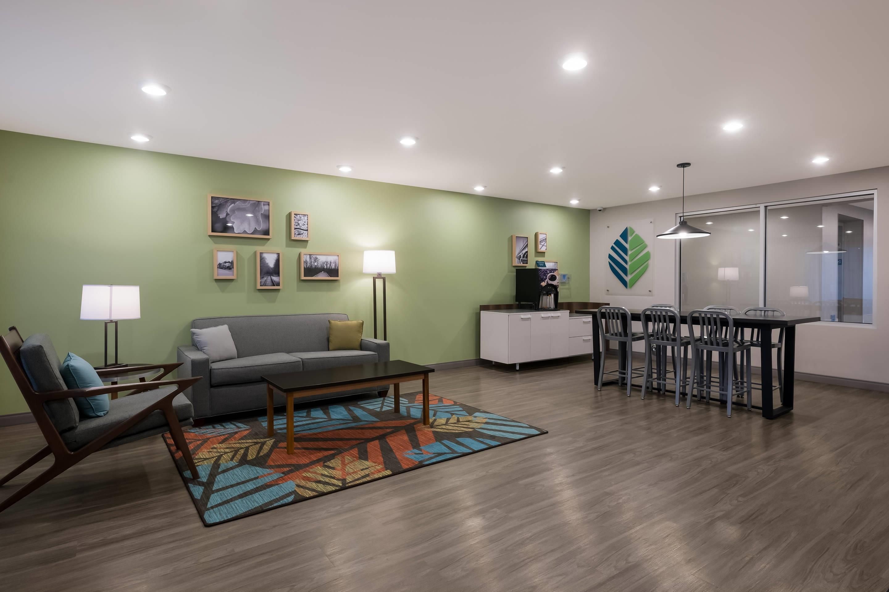 A modern living room with a sofa, coffee table, and chairs, a dining area with a table and chairs, and a kitchen area with cabinets and appliances.