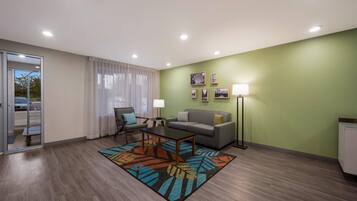 A modern living room with a sofa, armchair, coffee table, and a patterned rug.