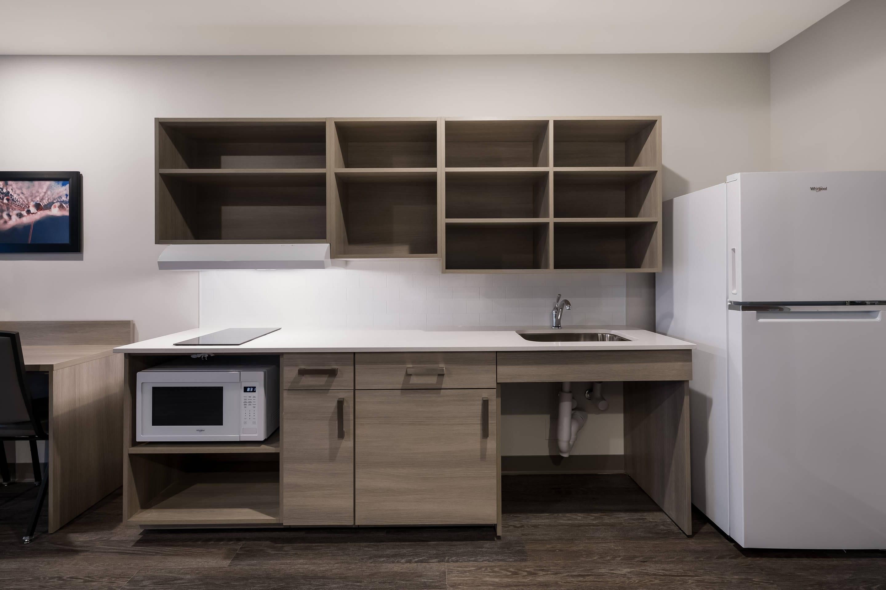 Una cocina moderna con microondas integrado, refrigerador y armarios de madera.