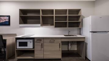 Una cocina moderna con microondas integrado, refrigerador y armarios de madera.